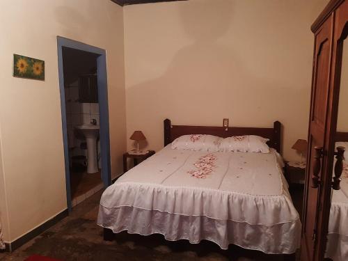 a bedroom with a bed with a white comforter at Casa Cabocla da Mantiqueira in Bueno Brandão