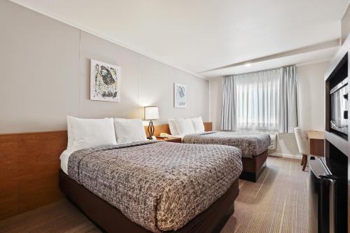 a hotel room with two beds and a television at Brookhurst Plaza Inn in Anaheim