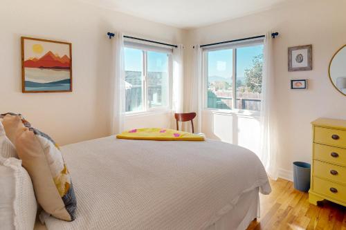 a bedroom with a white bed and two windows at Deep Blue Seaside in Monterey