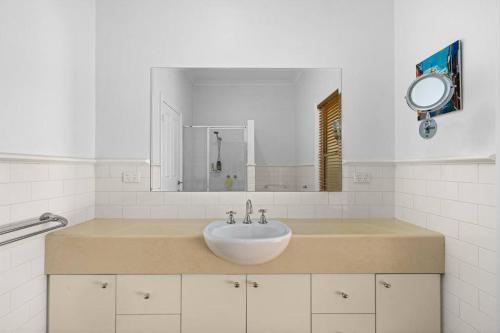 a white bathroom with a sink and a mirror at Stay at beautiful Rea in Shepparton