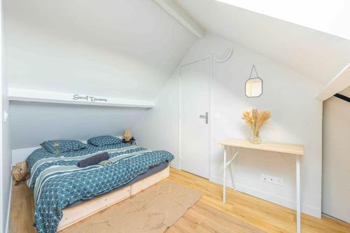 a white bedroom with a bed and a table at Le Petit Tremblay at 10 min Parc des Expos / CDG in Tremblay En France