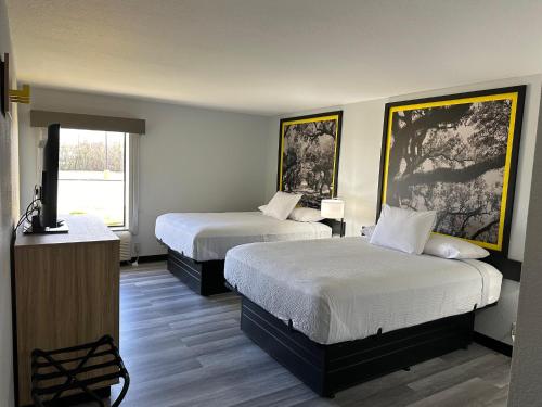 a hotel room with two beds and a television at Super 8 by Wyndham Alexandria LA in Alexandria