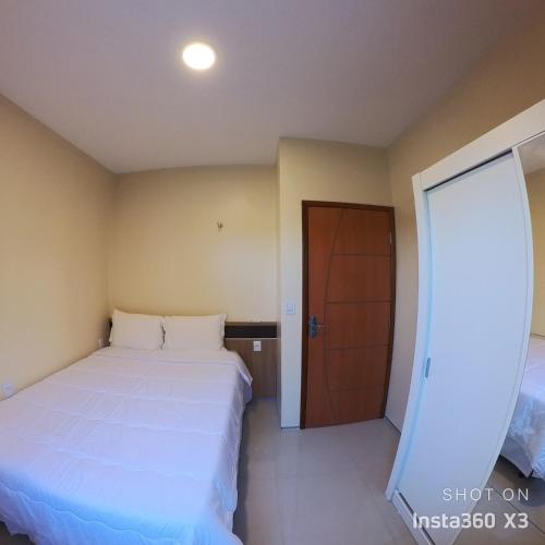 a bedroom with a large white bed and a door at Recanto dos Amigos in Santo Amaro