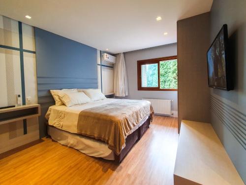um quarto com uma cama e uma televisão em Duplex Cobertura - Gramado Wish Serrano em Gramado