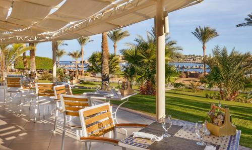 a patio with tables and chairs and palm trees at Steigenberger Coraya Beach - Adults Friendly 16 Years Plus in Coraya Bay