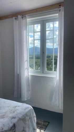 a bedroom with a large window with white curtains at Hacienda Bella Vista in Limones