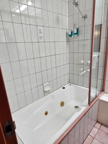 La salle de bains est pourvue d'une baignoire blanche et d'une douche. dans l'établissement Courtyard Motor Inn, à Shepparton