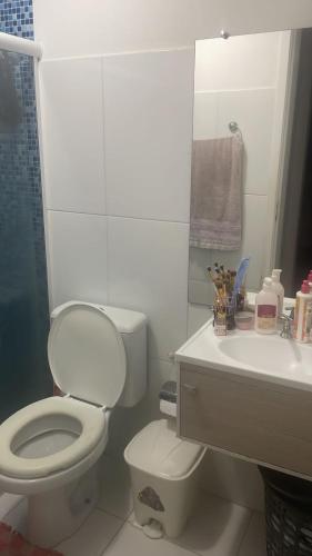Baño blanco con aseo y lavamanos en Apartamento tupã en Propriá