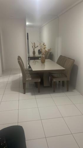 a dining room table and chairs with a vase on it at Apartamento tupã in Propriá
