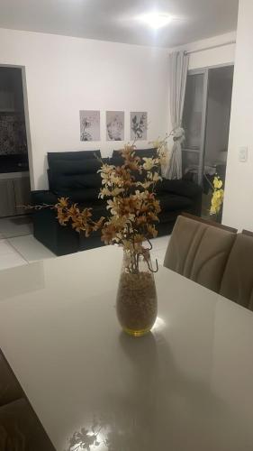 a vase with flowers on a table in a living room at Apartamento tupã in Propriá