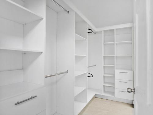 a walk in closet with white shelves and a glass door at Casa Bellavista Suites in San José