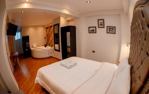 a bedroom with a white bed and a bathroom at Hotel Melthon Urbans in Ayacucho