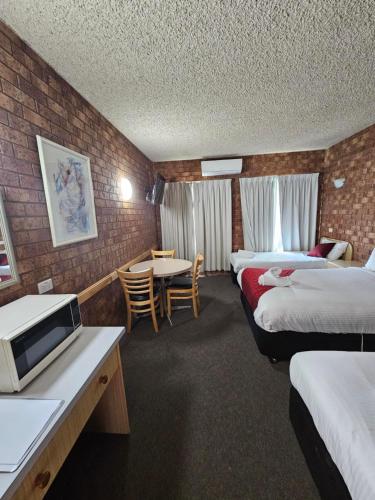ein Hotelzimmer mit 2 Betten und einem Tisch in der Unterkunft Courtyard Motor Inn in Shepparton