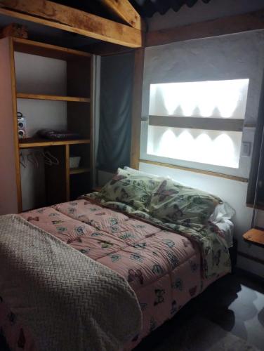 a bed in a bedroom with a window and a bedspread at Cabaña Zeus en Villas de San Felipe in Oicatá