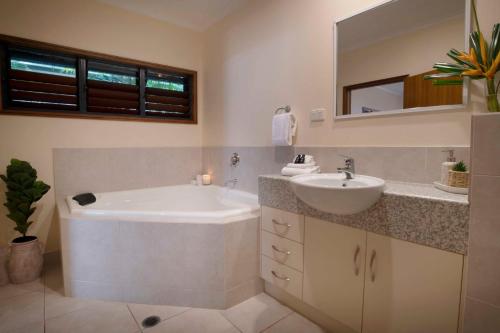 uma casa de banho com uma banheira, um lavatório e um espelho. em Latitude 17 - Suite 1 em South Mission Beach