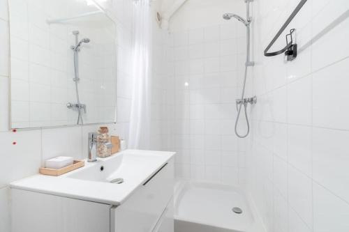 ein weißes Bad mit einem Waschbecken und einer Dusche in der Unterkunft BOULOGNE-PORTE D'AUTEUIL ROLAND GARROS TOURISME in Boulogne-Billancourt