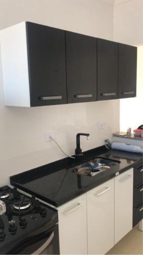a kitchen with a black sink and a stove at Apartamento Vila Tupi in Praia Grande