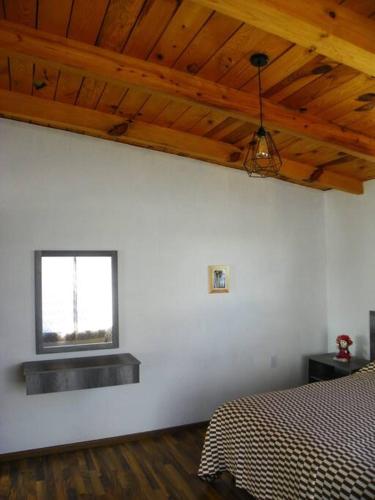 a white bedroom with a bed and a window at Casa Fresnos in Amealco