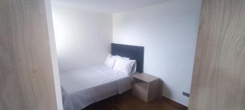 a small white room with a bed with a pillow at Apartamento de Lujo Sabaneta Jacuzzi in Sabaneta