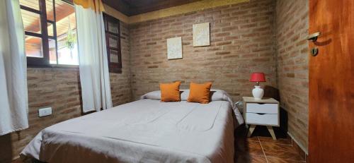 1 dormitorio con cama y pared de ladrillo en Casa de Campo Los Sauces in 