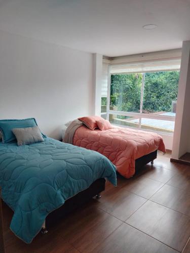 zwei Betten in einem Zimmer mit Fenster in der Unterkunft JOMAWA Vivienda Turística in Guayabal