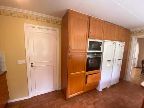 uma cozinha com armários de madeira e um frigorífico branco em Stockholm City Room for digital Nomads Elegance & Comfort - Tryggt & Privat - Room3 em Täby