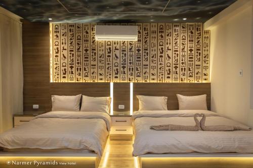 - une chambre avec 2 lits et un mur en bois dans l'établissement Narmer Pyramids View, au Caire