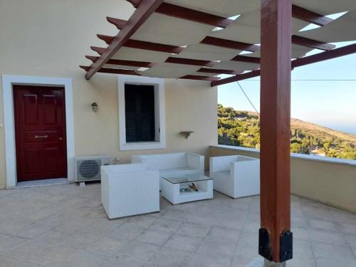 a patio with white furniture and a red door at Apoikia house with sea view 6max in Apoíkia