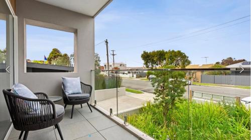 a balcony with chairs and a view of a street at Ocean Grove Breeze On The Terrace Coastal Apartment in Ocean Grove