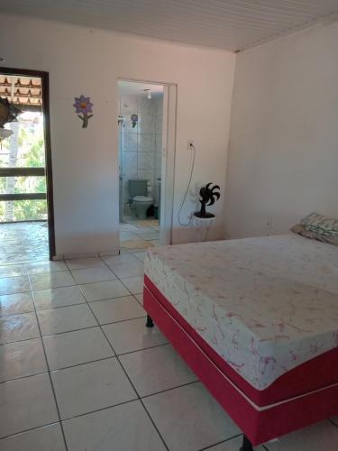 Casa de Férias Arborizada في كانافييراس: غرفة نوم بسرير وغرفة بحمام