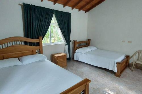 1 Schlafzimmer mit 2 Betten und einem Fenster in der Unterkunft Finca en Copacabana con piscina y cancha de futbol in Girardota