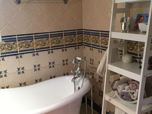 a bathroom with a tub and a tiled wall at Charmante maison historique avec jardin à Vadelaincourt - Charme, cheminée, et sérénité - FR-1-585-67 in Vadelaincourt