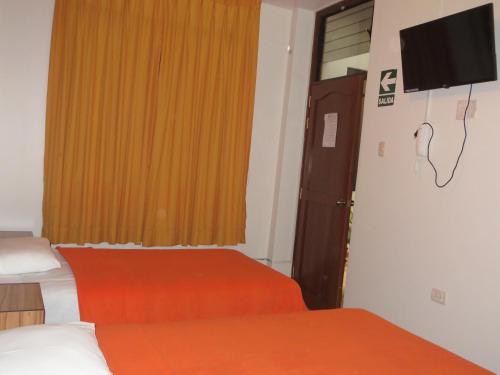 a room with two beds and a television on the wall at Hostal Hellen Ross in Nazca