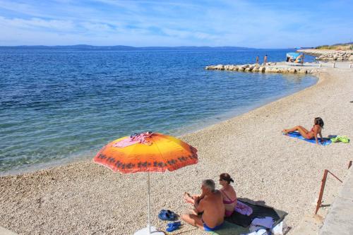 tres personas sentadas en la playa bajo un paraguas en Apartments with WiFi Split - 22126, en Split