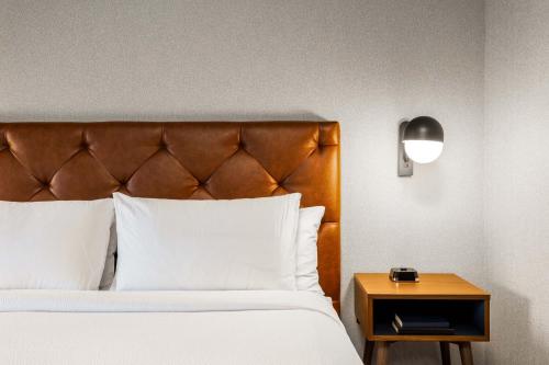 a bedroom with a bed with a wooden headboard and a table at Four Points by Sheraton Kelowna Airport in Kelowna