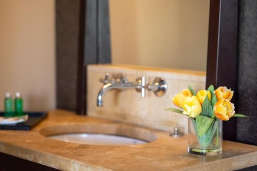 a vase of yellow flowers on a bathroom sink at Physacap Suites & Villas in Le François
