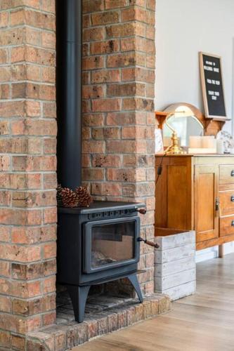 a brick fireplace with a black stove in a room at Willunga House - Fireplace Vineyard Views in Willunga
