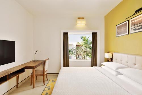 a bedroom with a bed and a desk and a television at Four Points by Sheraton Mahabalipuram Resort & Convention Center in Mahabalipuram