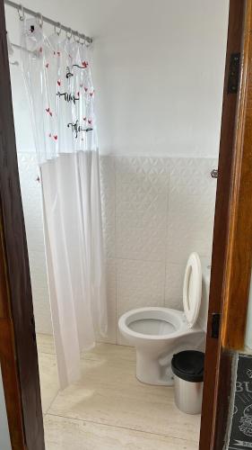 a bathroom with a toilet with a shower curtain at Apartamento Itanhanhem in Itanhaém
