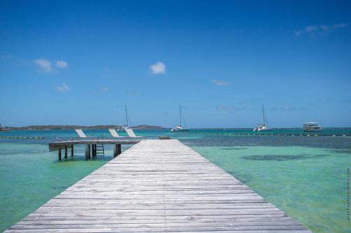 a wooden pier in the water with boats in the water at Physacap Suites & Villas in Le François