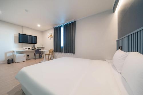 a bedroom with a white bed and a desk at Hotel gongjicheon 2 in Chuncheon