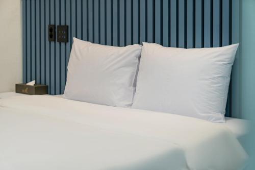 a white bed with white pillows and a blue wall at Hotel gongjicheon 2 in Chuncheon