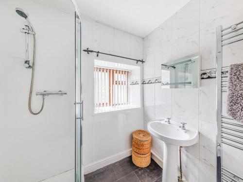 een witte badkamer met een wastafel en een douche bij 3 Bed in Corwen 90459 in Corwen