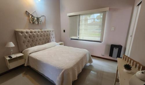 1 dormitorio con cama blanca y ventana en Casa en Santa Teresita en Santa Teresita