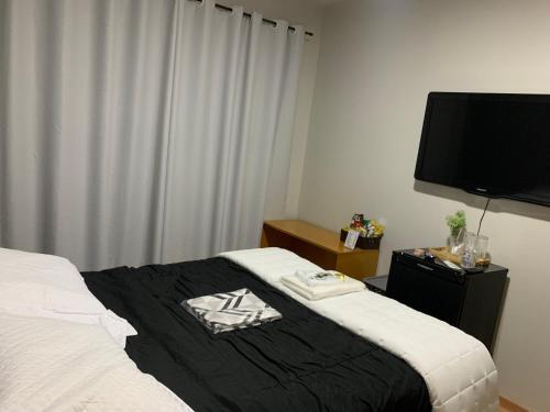 a bedroom with a bed and a flat screen tv at Quartos em Apartamento z4 - central in Maringá