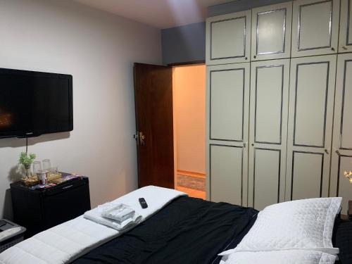 a bedroom with a bed and a tv on the wall at Quartos em Apartamento z4 - central in Maringá