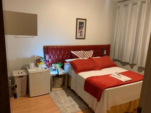 a bedroom with a large bed with red pillows at Quartos em Apartamento z4 - central in Maringá