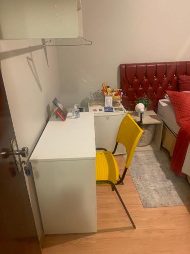 a room with a white desk and a yellow chair at Quartos em Apartamento z4 - central in Maringá
