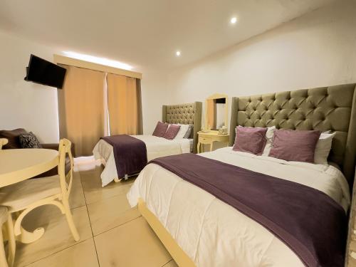 a hotel room with two beds and a table at Hotel-Spa Posada Bonita in Dolores Hidalgo