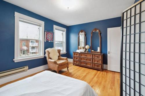 um quarto com paredes azuis, uma cadeira e um espelho. em Spacious & Cozy Home in Highfield St Moncton em Moncton